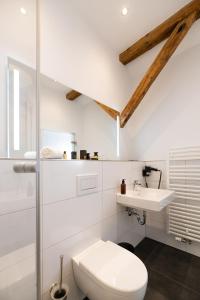 a white bathroom with a toilet and a sink at Nikii Boutique Hotel in Leverkusen