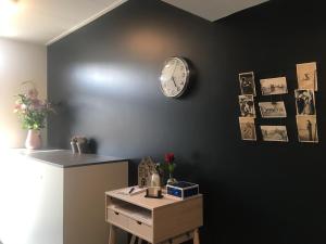 a black wall with a clock and a table at Pakhuis 5 in Katwijk aan Zee