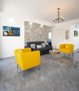 sala de estar con sofá y 2 sillas amarillas en Arricàmpati Apartments Villa & Bringo Car Rental, en Carini