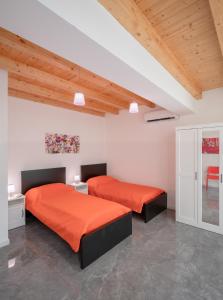 two beds with orange sheets in a room at Arricàmpati Apartments Villa & Bringo Car Rental in Carini