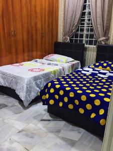 two beds with polka dot sheets in a room at Bayan Baru Homestay @ Taman Sri Nibong in George Town