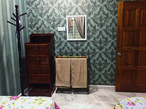 Bayan Baru Homestay @ Taman Sri Nibong في جورج تاون: غرفة نوم مع ورق جدران أخضر وخزانة ومرآة