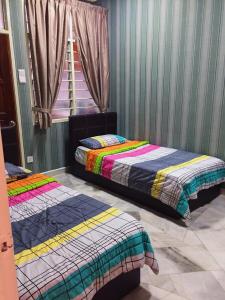 two beds sitting in a room with a window at Bayan Baru Homestay @ Taman Sri Nibong in George Town