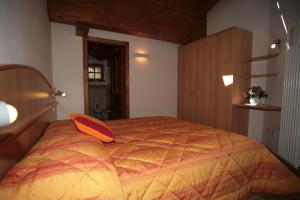 - une chambre avec un grand lit et un oreiller orange dans l'établissement Villetta ai Pini Deluxe, à Canazei