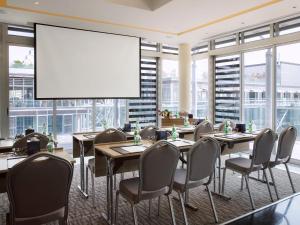 a conference room with tables and chairs and a large screen at The Boulevard Arjaan by Rotana in Amman
