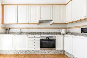a white kitchen with white cabinets and a sink at Townhouse La Tejita in La Tejita