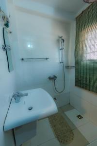 a white bathroom with a sink and a shower at Rans Hill Lodge in Cape Coast