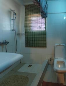 uma casa de banho com uma banheira, um WC e uma janela. em Rans Hill Lodge em Cape Coast