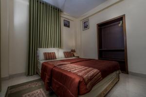 1 dormitorio con 1 cama y una ventana con cortinas verdes en Rans Hill Lodge en Cape Coast