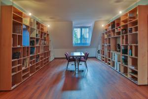 a library with two chairs and a table and bookshelves at Lipa Hotel és Étterem in Szentgotthárd