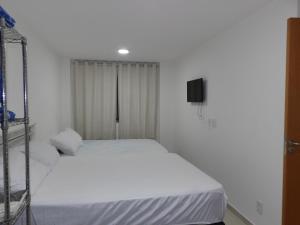Habitación blanca con 2 camas y TV. en Arraial do Cabo, en Arraial do Cabo