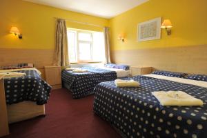 a hotel room with three beds and a window at Acton Town Hotel in London