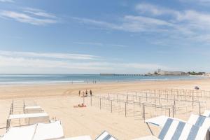 a beach with white chairs and the ocean at Résidence Pierre & Vacances La Baie des Sables in Les Sables-d'Olonne