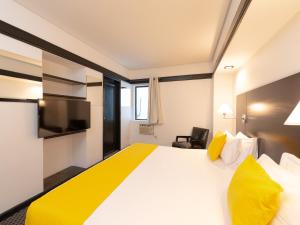 a hotel room with a large white bed with yellow pillows at Hotel Normandie in Sao Paulo