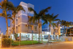 a building with palm trees in front of it at Marazul Apart Hotel 2 in Florianópolis