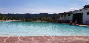 a large swimming pool with people sitting around it at Hostal La Guineu in Viladrau