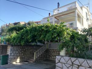a villa with a hedge in front of a building at Apartments Boric in Lopar