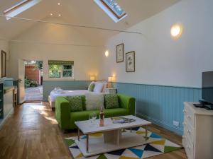 a bedroom with a bed and a green couch at Bluebell Studio in Saxmundham