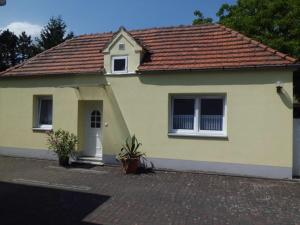una pequeña casa amarilla con techo marrón en Ferienhaus Ulbricht beim Senftenberger See, en Hosena