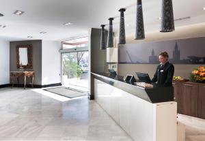 a woman sitting at a counter in a lobby at Catalonia Hispalis in Seville