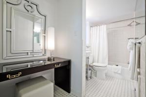 a bathroom with a toilet, sink, mirror and bath tub at State Plaza Hotel in Washington, D.C.