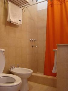 La salle de bains est pourvue d'un rideau de douche orange et de toilettes. dans l'établissement Rinconcito en Tilcara, à Tilcara