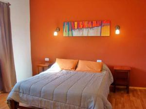 a bedroom with a bed with an orange wall at Rinconcito en Tilcara in Tilcara