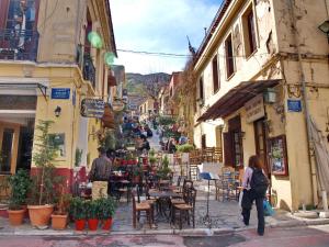 een groep mensen die door een straat lopen met tafels en stoelen bij Caryatis Apartment in Athene