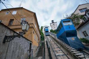 a blue train on the tracks next to a building at TOP Apartman in Zagreb