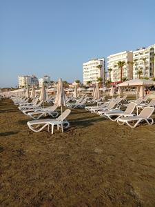 een rij ligstoelen en parasols op een strand bij Mikis Studio Type Aprt. in Larnaka