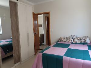 1 dormitorio con cama multicolor y espejo en Apto 2 dorm a 750m da praia, en Florianópolis