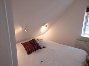a bedroom with a white bed with a red pillow at Aalborg City Rooms ApS in Aalborg