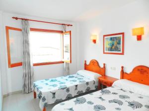 two beds in a room with a window at Apartaments Marina Sol i Pins in Cala Figuera +36 photos