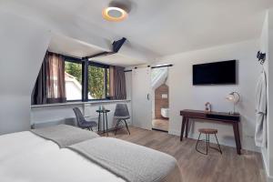 a bedroom with a bed and a desk and a television at Boutique Hotel Bellevue in Blaricum