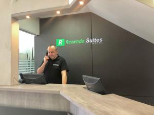 a man talking on a cell phone at a reception desk at Rezende Suítes Hotel in Balneário Camboriú