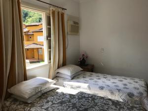 een slaapkamer met een bed en een raam bij Linda casa em condomínio in Paraty +49 foto's