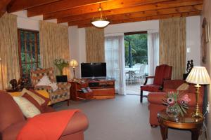 a living room with a couch and a tv at Plotsklaps Self Catering Cottage in Tokai