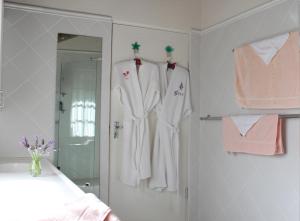 a bathroom with white robes hanging on a wall at Plotsklaps Self Catering Cottage in Tokai