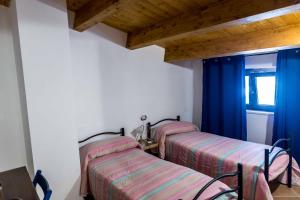 two beds in a room with blue curtains at La casetta al lago in Scanno