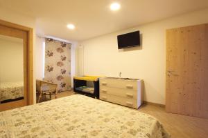カヴァレーゼにあるAppartamento Dianaのベッドルーム(ベッド1台、ドレッサー、テレビ付)