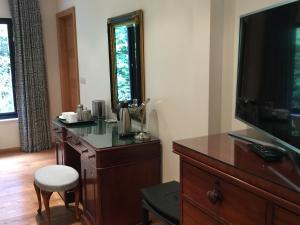 a room with a dresser with a television and a chair at White Lodge B&B in Cooksbridge