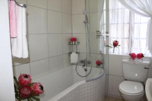 a bathroom with a tub and a toilet and red roses at Plotsklaps Self Catering Cottage in Tokai