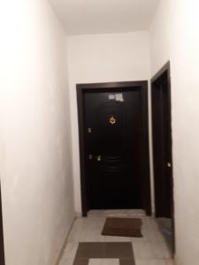 une porte noire dans un couloir avec du carrelage. dans l'établissement Boshku apartament, à Durrës