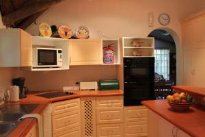 a kitchen with white cabinets and a black refrigerator at Plotsklaps Self Catering Cottage in Tokai