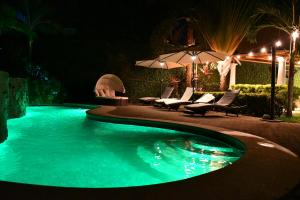a swimming pool at night with chairs and an umbrella at 12B Jaco Sol Quadplex in Jacó