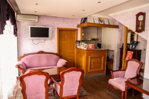 ein Wohnzimmer mit rosa Stühlen und einem TV in der Unterkunft Bed and Breakfast Vijecnica in Sarajevo
