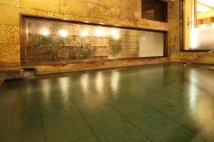 a swimming pool with a tile floor and a window at Tsuruya Ryokan in Karuizawa