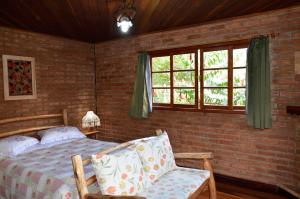 una camera con letto, sedia e finestre di Pousada Das Araucárias a Visconde De Maua