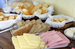 a table topped with different types of bread and pastries at Pousada Cantagalo in Itaipava