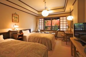 a hotel room with two beds and a television at Tsuruya Ryokan in Karuizawa